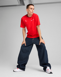 Front view of a male model wearing a red F1 Essential Relaxed Tee with dark wide-leg jeans.