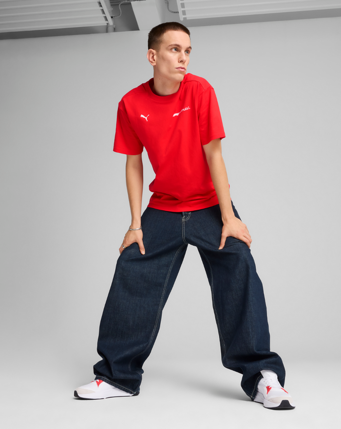 Front view of a male model wearing a red F1 Essential Relaxed Tee with dark wide-leg jeans.