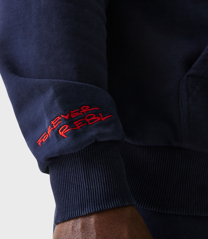 Close up of navy hoodie sleeve with red embroidered text near the cuff