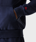 Back view of man in navy oversized hoodie wearing a dark cap with red adjustable strap