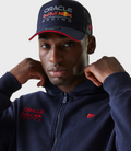 Front view of a model wearing a navy hoodie with Oracle Red Bull Racing embroidery on the left chest and a navy cap with the same branding