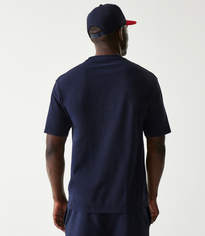 Back view of a man in a navy oversized Oracle Red Bull Racing t shirt and cap