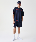 Front view of a male model in the navy mesh tee with red logo patches and white sneakers.