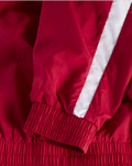 Close up of red jacket sleeve with white diagonal stripe and elastic cuff
