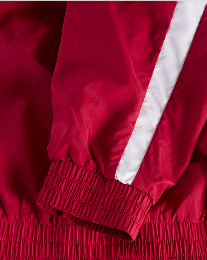 Close up of red jacket sleeve with white diagonal stripe and elastic cuff