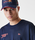 Close up of navy blue mesh shirt and cap featuring Oracle Red Bull Racing branding and Forever REBL lettering.