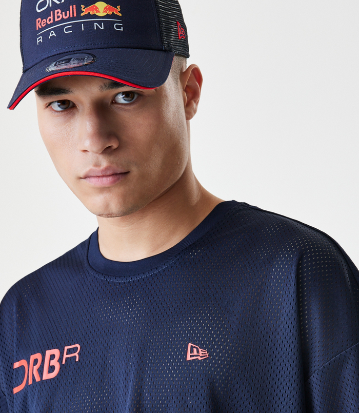 Close up of navy blue mesh shirt and cap featuring Oracle Red Bull Racing branding and Forever REBL lettering.