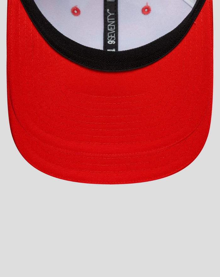 Red curved brim of a baseball cap with black edge and visible top stitching
