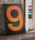 Framed McLaren F1 2024 Constructors Champions poster with orange ring and blueprint car drawings against a textured wall