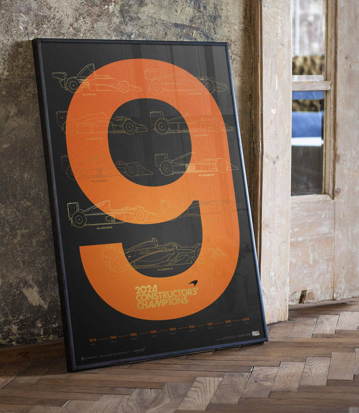 Framed McLaren F1 2024 Constructors Champions poster with orange ring and blueprint car drawings against a textured wall