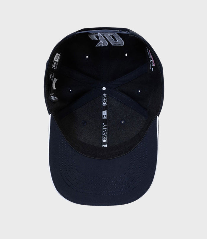 Interior view of a navy cap showing branding labels and the adjustable snap strap at the back