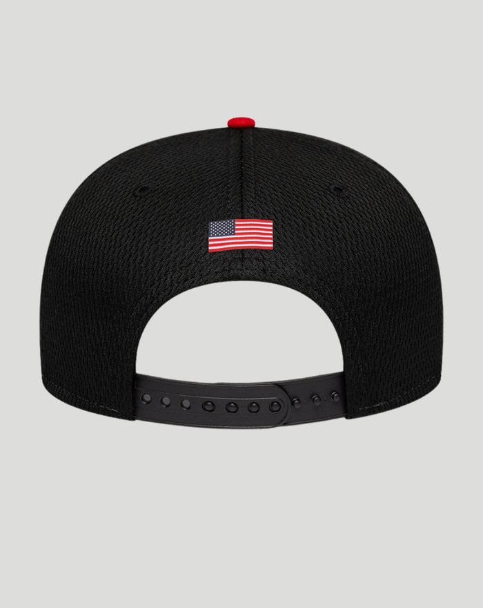 Back view of the cap showing a small American flag patch on the black crown and an adjustable strap with multiple holes