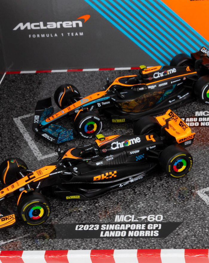 Two black and orange 1:43 McLaren F1 cars on a diorama track with McLaren branding.