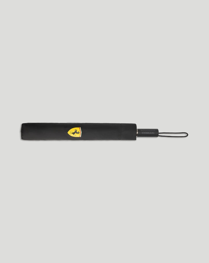Folded black Scuderia Ferrari umbrella with yellow Ferrari crest on the sleeve and wrist strap
