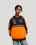 Child model wearing a black and orange McLaren Junior Team Hoodie in Papaya color