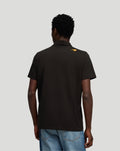 Back view of black McLaren Small Logo Polo with orange emblem on the upper back