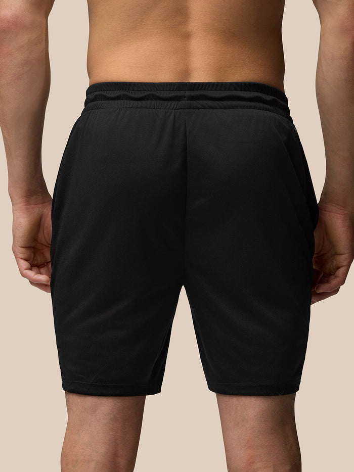 Back view of a male model wearing black Adapt Training 7 inch shorts with an elastic waistband.