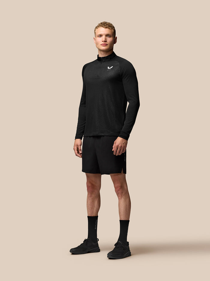 Full-body shot of a male model wearing black Adapt Training gear with a long sleeve top and 6in shorts