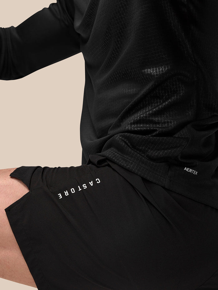 Close-up of black Adapt Training 6in shorts with Castore branding on the left thigh and Aertek branding at the right rear