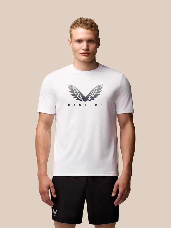 Male model in white Adapt Short Sleeve Graphic T shirt with a wing logo on the chest and black shorts
