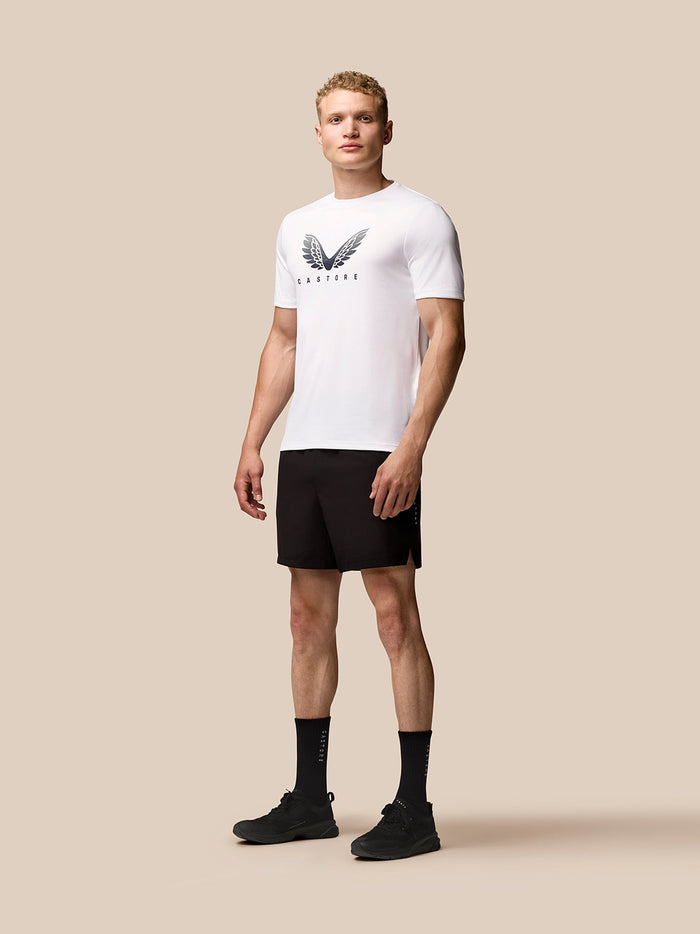 Full-body front view of white Adapt Training T-Shirt with Castore wings logo paired with black shorts and socks