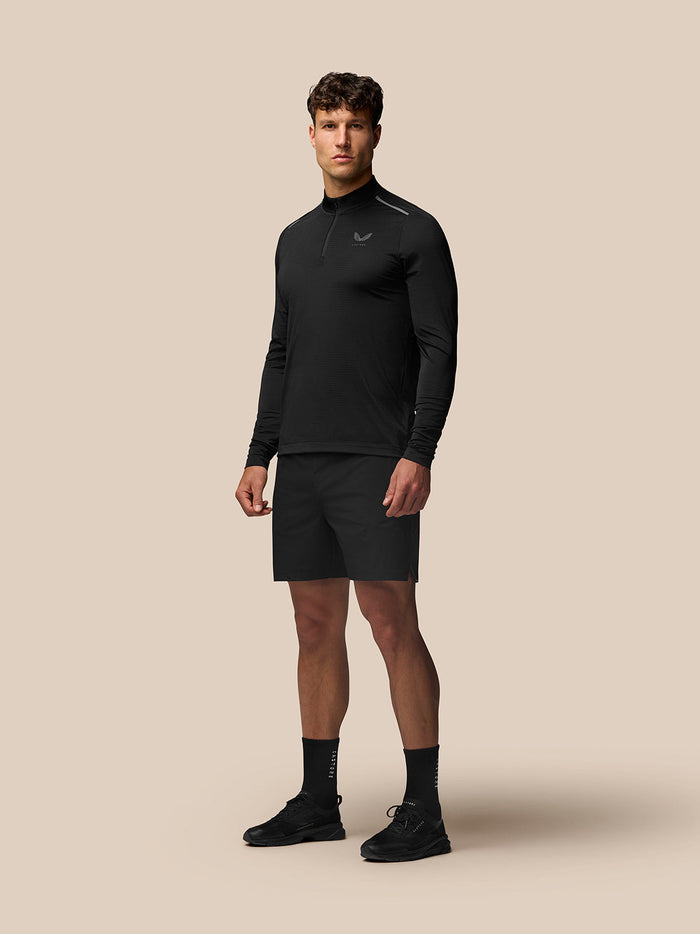 Male model wearing Apex Training 1/4 Zip Top in black with stand collar and reflective branding.
