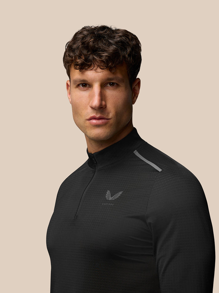 Male model wearing Black Apex Training 1/4 Zip Top with stand collar and textured fabric; Castore logo on chest