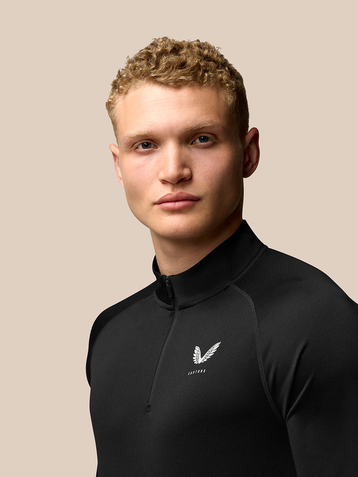 Close-up of black Adapt Training 1/4 Zip Top with zip collar and Castore logo on the chest