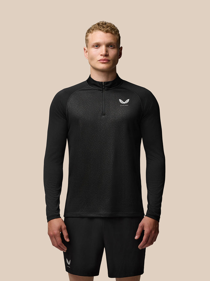 Male model wearing black Adapt Print 1/4 Zip Top with all over geometric pattern and Castore branding