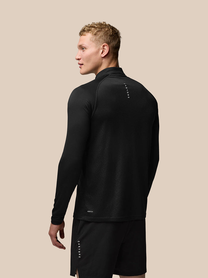 Back view of a man wearing black Adapt Print 1/4 Zip Top with subtle geometric pattern and Aertek branding at the lower back