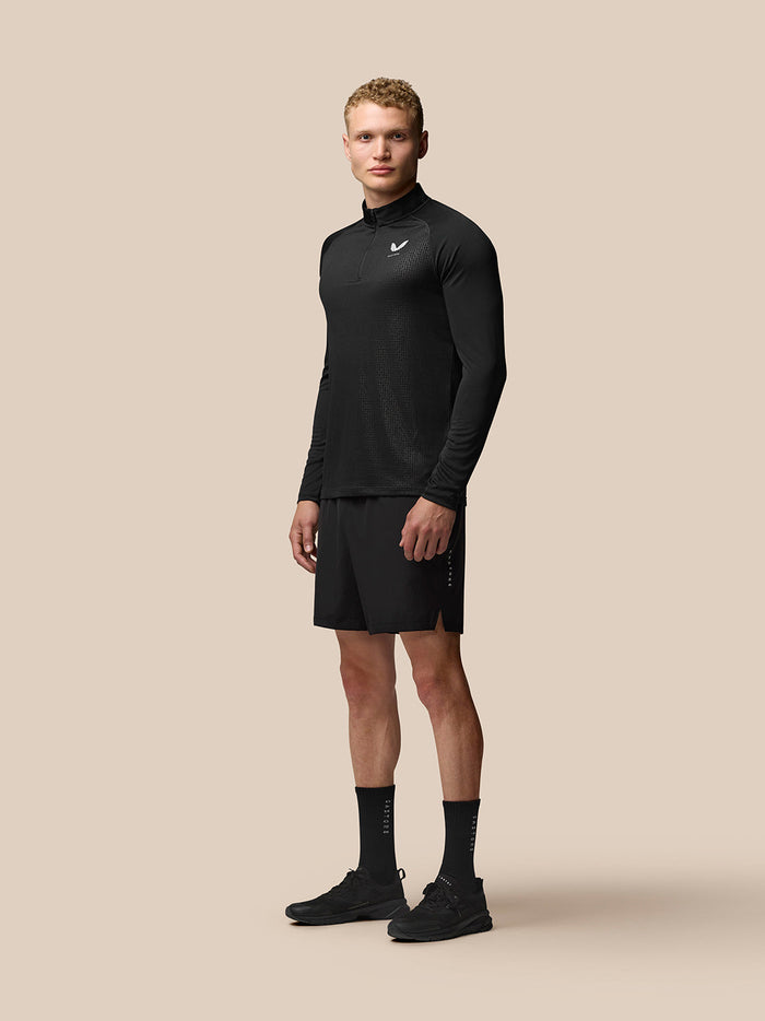 Full body front view of man in black Adapt top and shorts with textured geometric pattern and athletic fit.