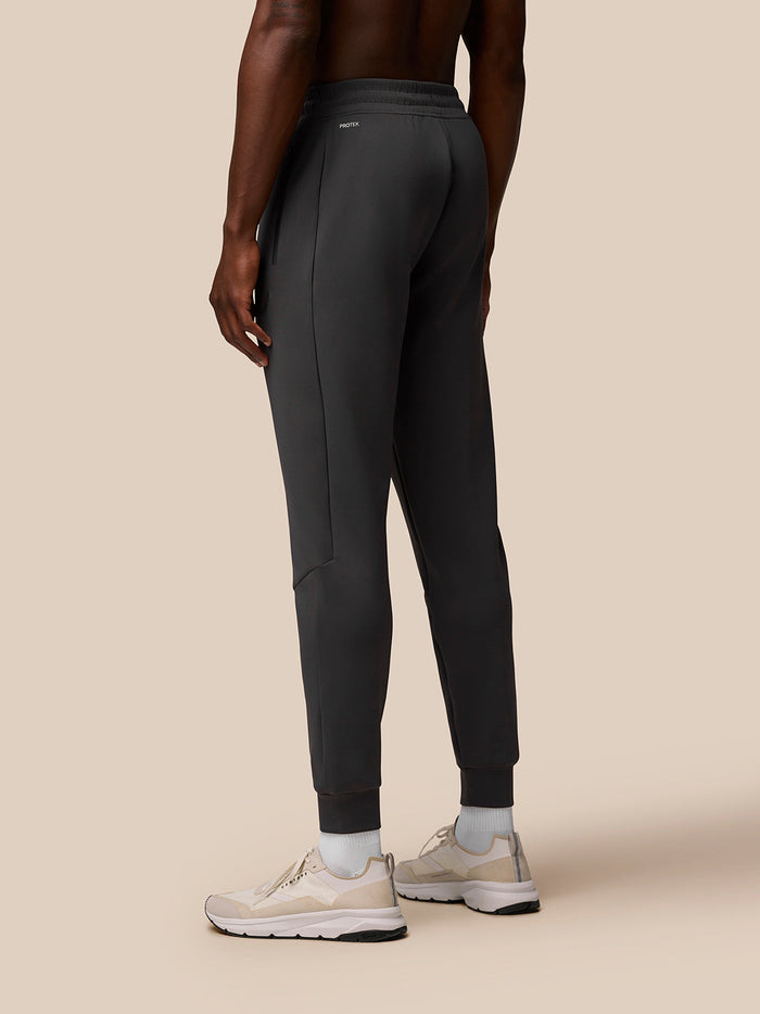 Back view of a male model wearing charcoal Flex Joggers with cuffed ankles.