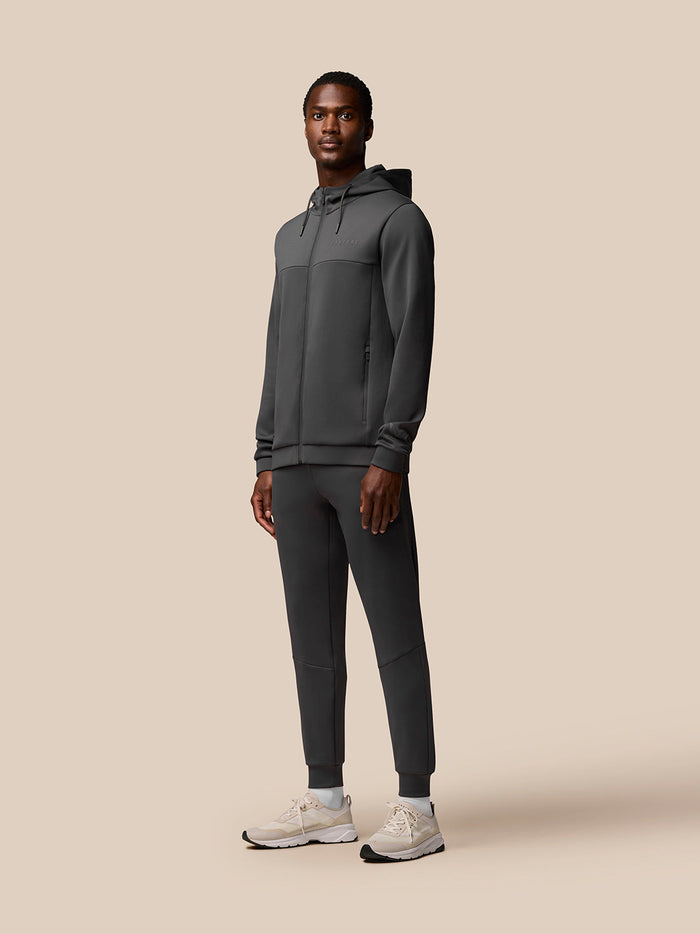 Full body view of a model wearing charcoal Flex Joggers with a matching hooded jacket in a neutral studio.