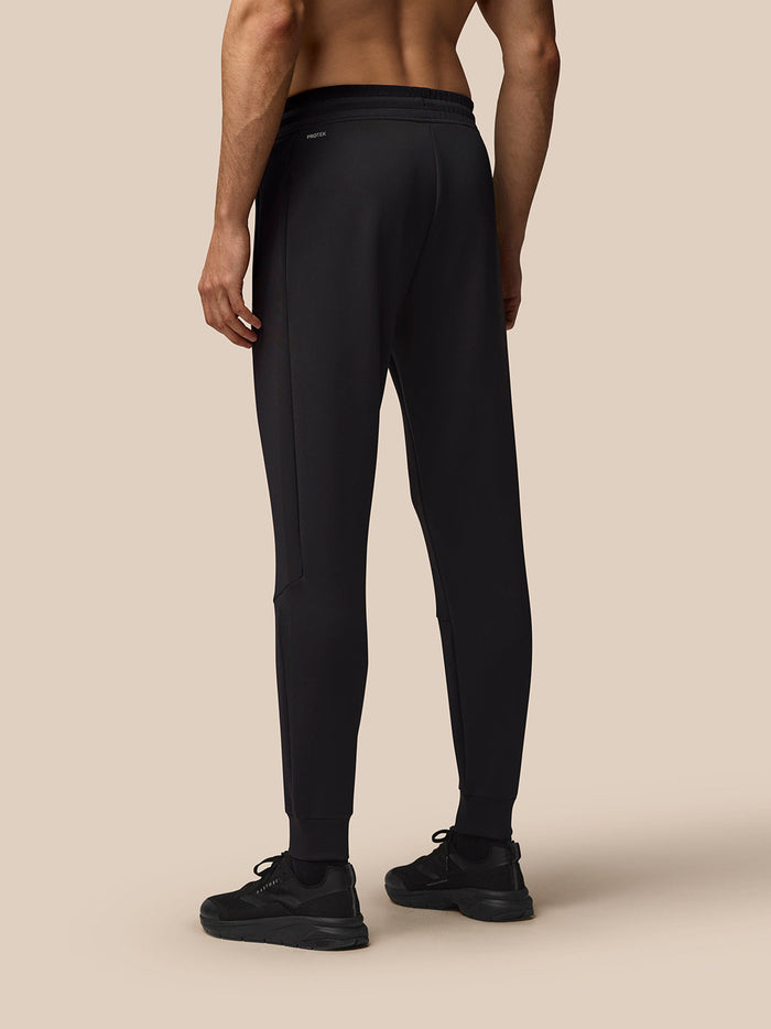 Back view of a man in black Flex Joggers showing Protek branding at the left rear.