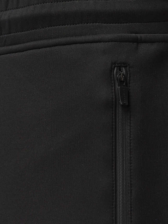 Side view of a man in black Flex Joggers with Castore branding on the left thigh.