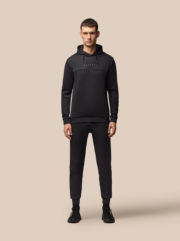 Full body shot of man in black Flex Hoodie and matching joggers with Castore branding.