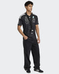 Model wearing black Mercedes AMG Petronas F1 Team Driver T-Shirt with lanyard and small crossbody bag.