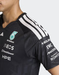 Front view of black Mercedes driver T shirt with Petronas emblem on the chest and teal neckline trim.