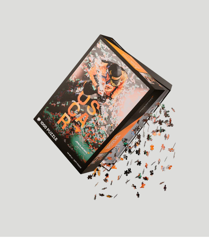 Angled view of a McLaren Oscar Piastri 1000 piece puzzle box with a celebratory race photo and confetti.