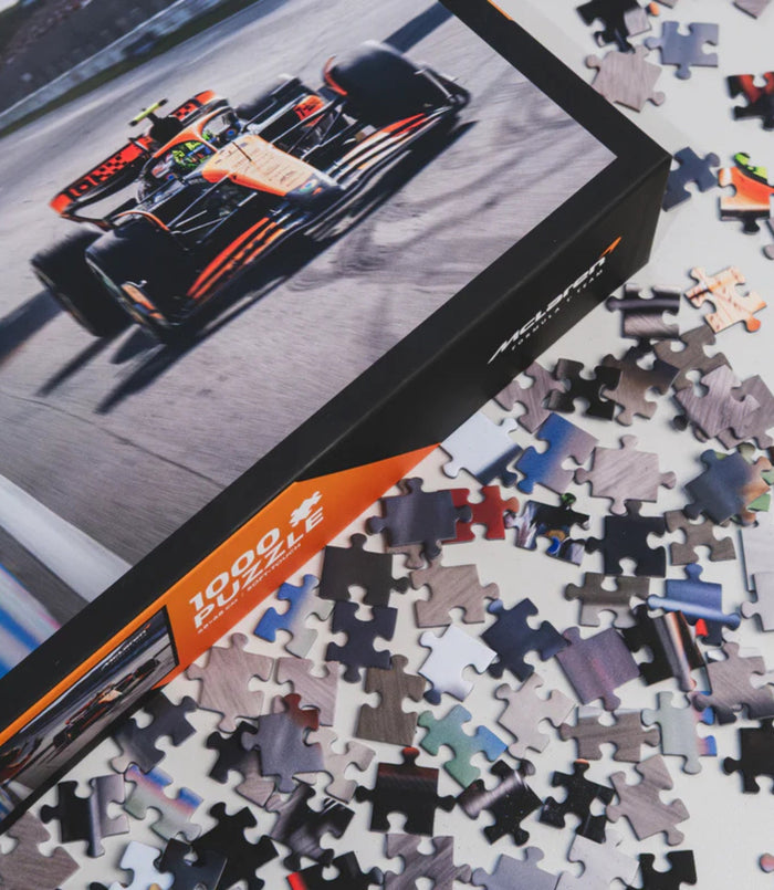 Puzzle box cover shows a McLaren Formula 1 car on track with orange accents and puzzle pieces scattered nearby.