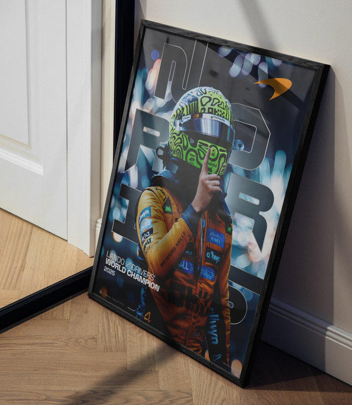 Framed Lando Norris 2025 World Drivers Championship poster leaning on the floor beside a white cabinet.