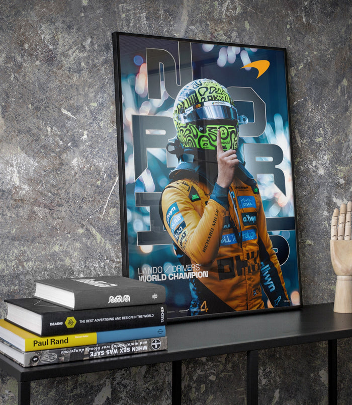 Framed Lando Norris poster displayed on a textured wall at an angle featuring a neon green helmet image.