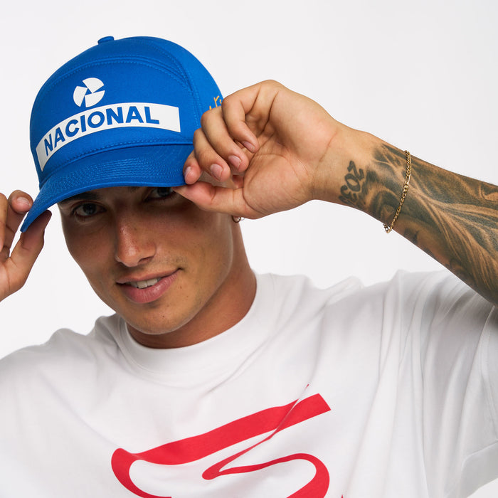 Blue Senna Nacional cap held by hand with Senna signature in gold on the side and Nacional patch visible