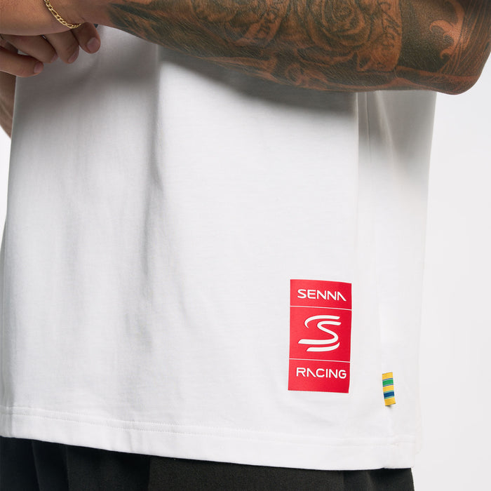 Back view close up of wearer in white Senna T shirt showing a red Senna patch near the lower back