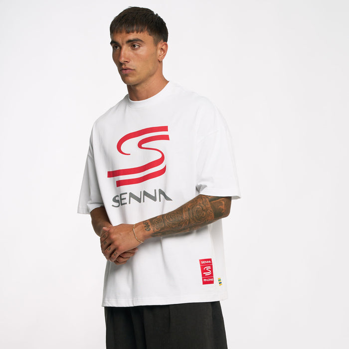 Male model wearing white Ayrton Senna oversized graphic T shirt with a red curved logo on chest