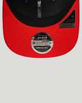 Close-up of red underside of curved brim on the black 9SEVENTY cap with a 9SEVENTY stretch snap badge.