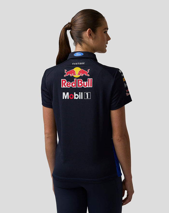 Back view of a woman wearing a navy Oracle Red Bull Racing team polo with large Red Bull and Mobil 1 logos