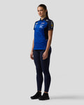Side profile of a woman wearing a blue Oracle Red Bull Racing team polo with sponsor branding across the chest
