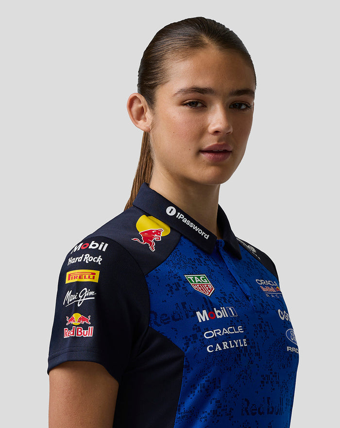 Close-up of a woman wearing a blue Oracle Red Bull Racing team polo with multiple sponsor logos