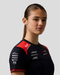 Three quarters view of a woman wearing a black Haas Team women's driver T shirt with red shoulder panels.